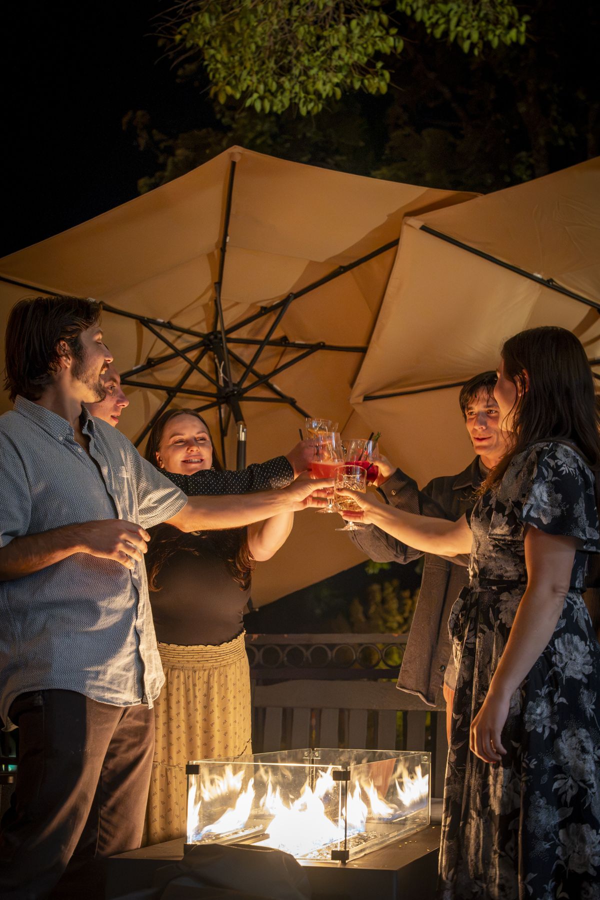 Friends toasting around the fire table on the patio